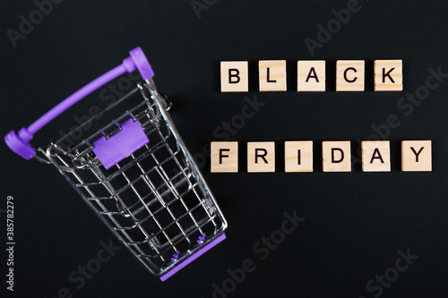 Black Friday, sale message, sign. Black friday sale poster or banner. Shopping trolley and wooden letters on black background. 