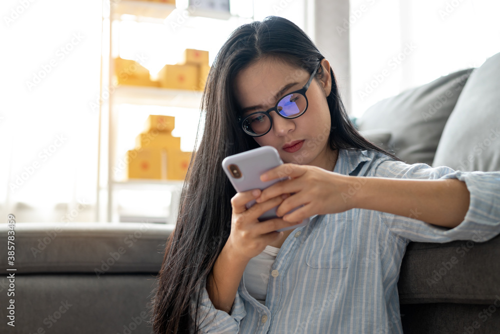 Small business owner woman is using smartphone for checking product to send customer for the online order Small business owner woman is using smartphone for checking product to send customer for the online order
