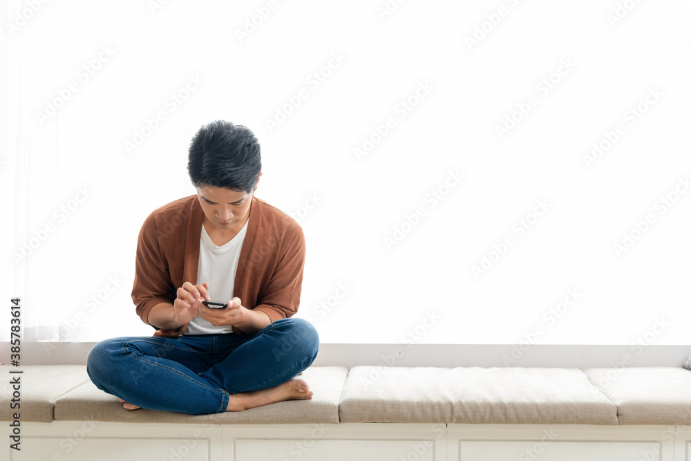 A young man is using a mobile phone in front of a white background  (work from home)