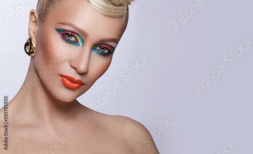 Frontal fashionable woman with colorful makeup and hairstyle, with bare shoulders.
