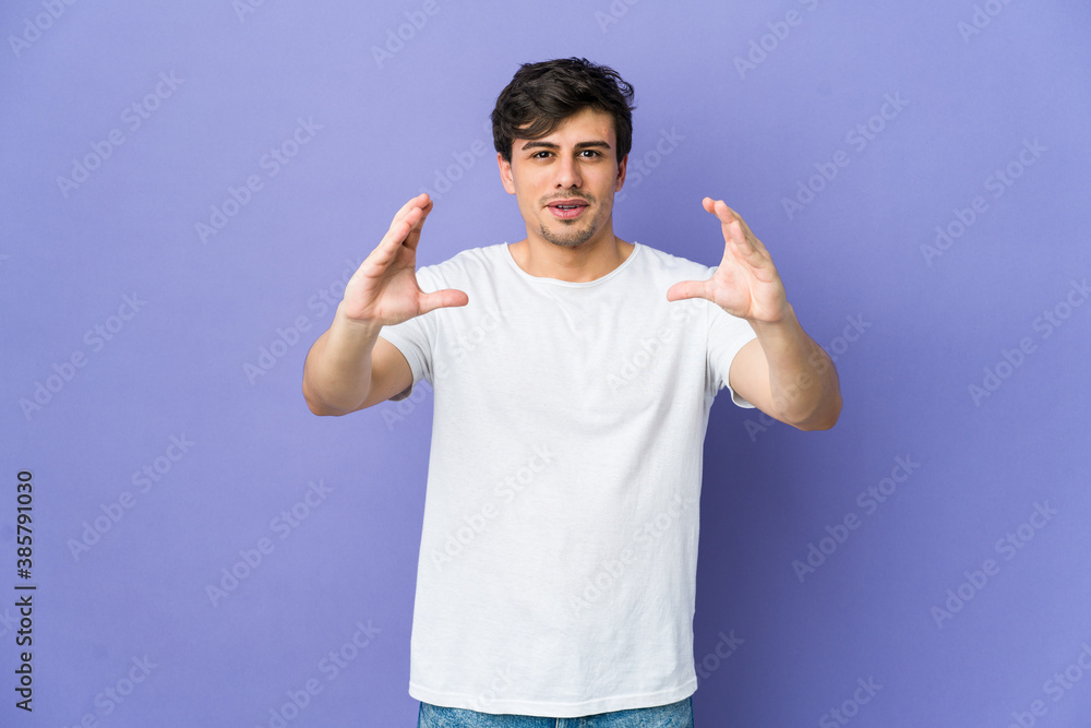 Young cool man holding something with palms, offering to camera.