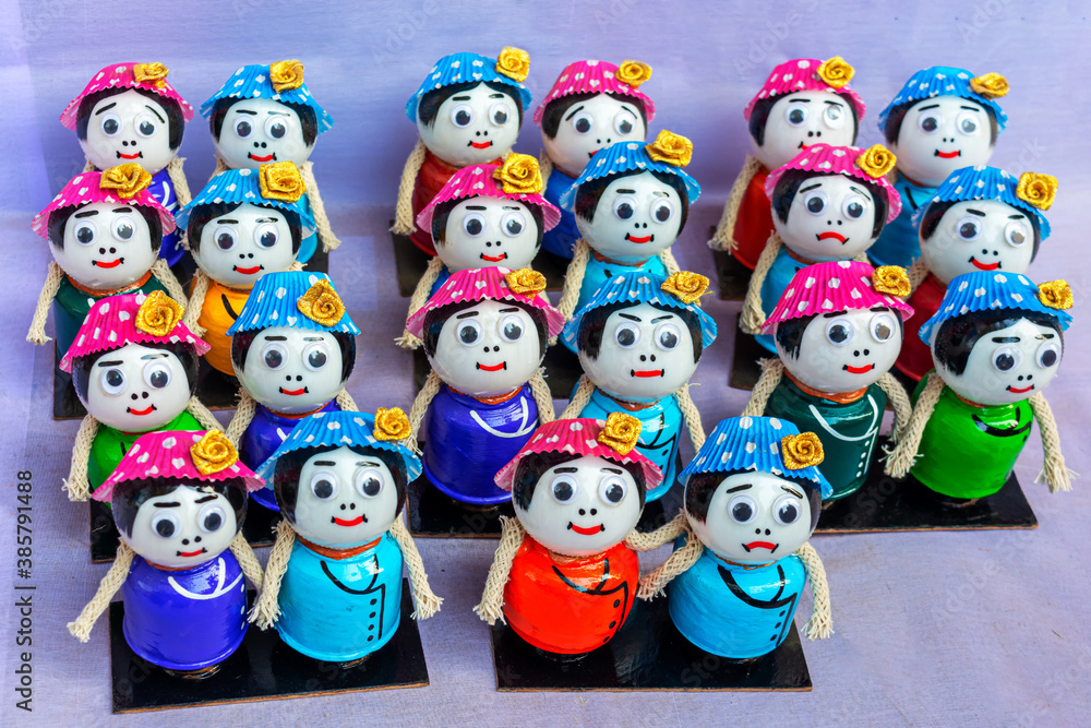A collection of colorful traditional wooden dolls or channapatna toys are displayed for selling in handicraft fair.