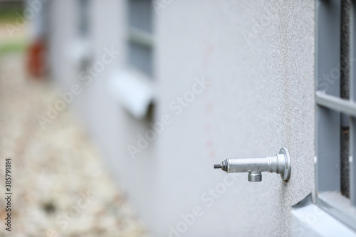 Metal water tap in a grey building. Faucet in a residential building.