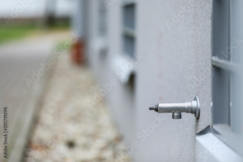 Metal water tap in a grey building. Faucet in a residential building.