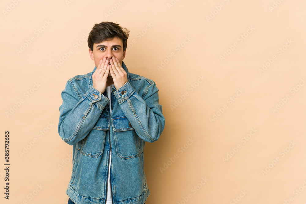 Young cool man shocked, covering mouth with hands, anxious to discover something new. Young cool man shocked, covering mouth with hands, anxious to discover something new.
