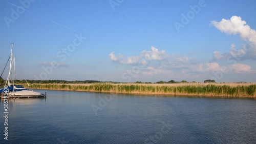 Wallpaper Mural Time-lapse scenery at Lake Neusiedlersee in summer afternoon. Boats pass by in a sheltered bay with a jetty and a belt of reeds, clouds form up in the blue sky. Torontodigital.ca