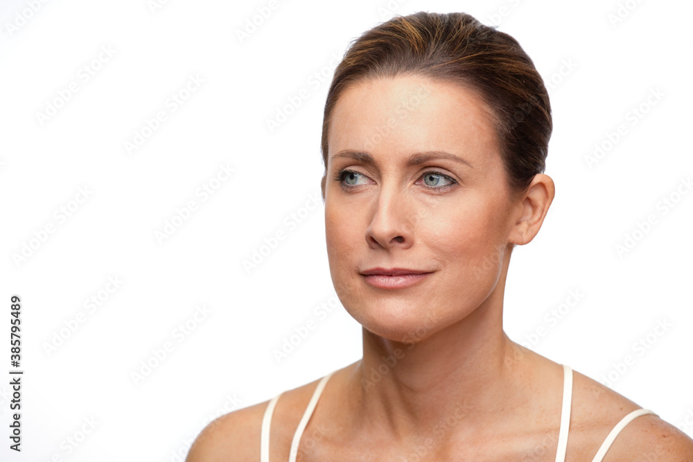 Portrait of middle aged white woman with brown hair pulled back, looking off camera straight faced