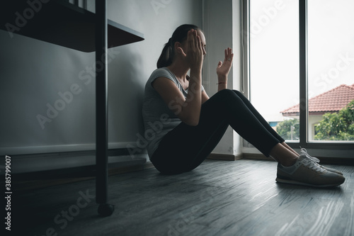Woman with a mental health illness sitting sad in the room with a headache and stress a home quarantine fear Coronavirus or COVID-19 virus outbreak and depressing business economy. Healthcare concept.