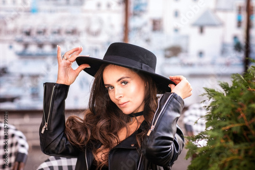 Attractive young woman in leather jacket and hat sitting in cafe. Copy space.