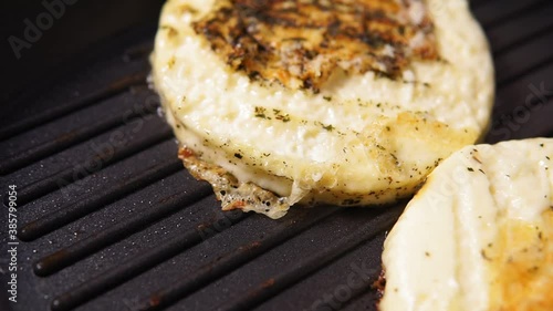 delicious pieces of halumi cheese cooking on a hot iron stove with smoke coming out photo