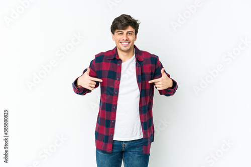 Young cool man person pointing by hand to a shirt copy space, proud and confident