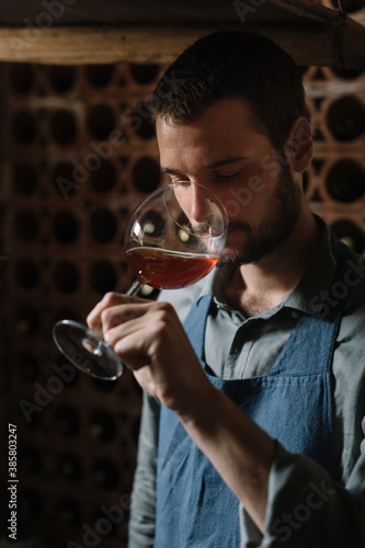 Young man tasting wine from glass in cellar photo