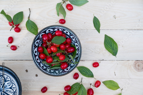 Bowl with leaves and fresh Cornelian cherries (Cornus mas) photo