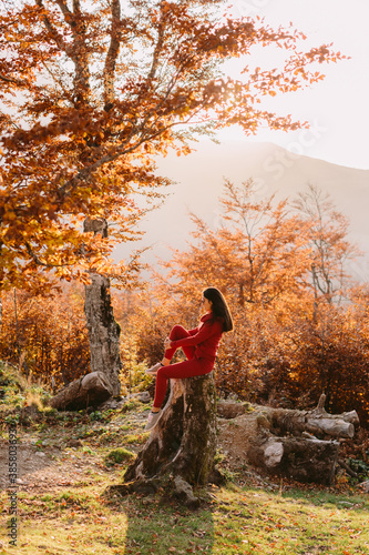 woman relax in autumn forest. Beautiful female walk in warm outfit outdoors. Mountains background. © shevtsovy