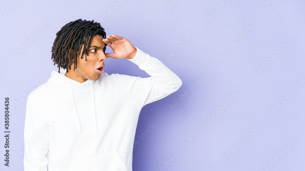 Young african american rasta man looking far away keeping hand on forehead. Young african american rasta man looking far away keeping hand on forehead.