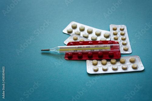 Colored tablets  capsules  fish oil. Treatment with drugs. Medicines  thermometer on a blue background. Macro photography  soft focus.