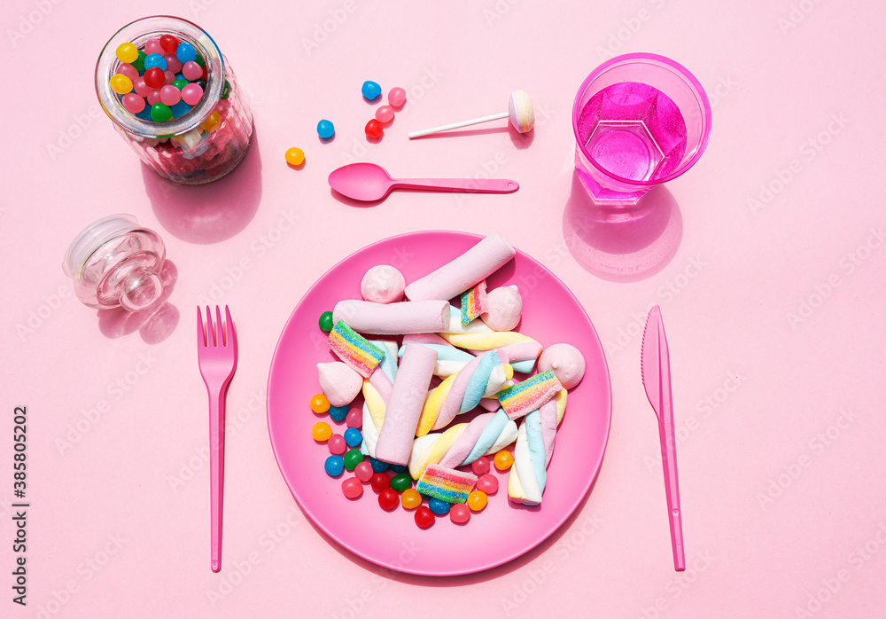 Studio shot of glass of water, jar of candies and plastic plate filled with various sweets Studio shot of glass of water, jar of candies and plastic plate filled with various sweets