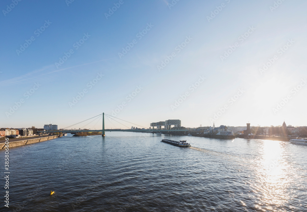 Germany, North Rhine-Westphalia, Cologne, Sun setting over Rhine with Rheinauhafen and Severin Bridge in background Germany, North Rhine-Westphalia, Cologne, Sun setting over Rhine with Rheinauhafen and Severin Bridge in background