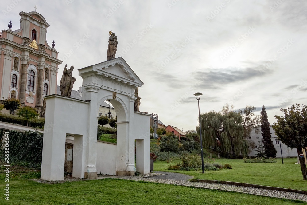 The white baroque entrance gate in Fulnek, Czech Republic with a Kostel Nejsvetejsi Trojice (Holy Trinity Church) in background