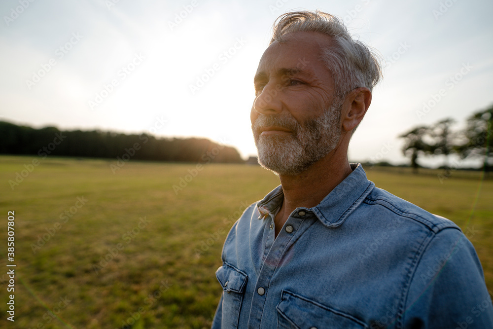 Content mature man on a meadow in the countryside Content mature man on a meadow in the countryside