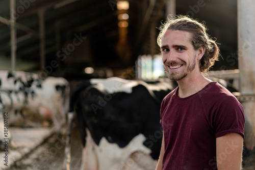 Portrait of a smiling young farmer at cow house on a farm