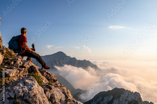 Hiker admiring view while sitting on top of mountain peak at Bergamasque Alps, Italy photo