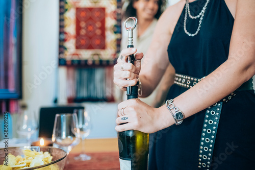 Woman opening wine bottle during social gathering at home photo