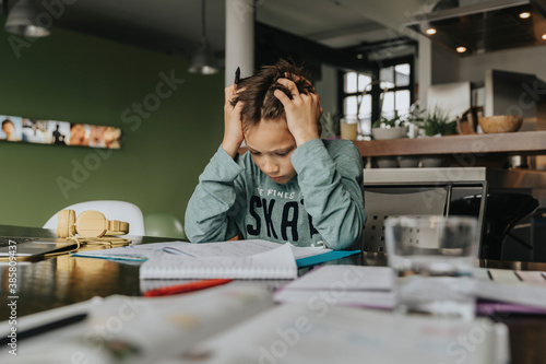 Schoolboy learning at home, head in hands, solving problem