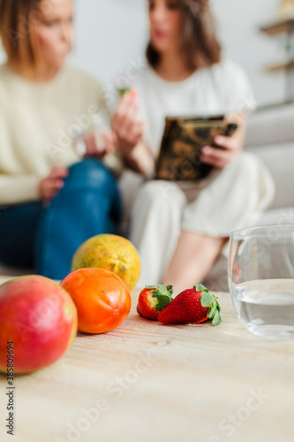 Fruits kept on table with women in background discussing about nutrition at home