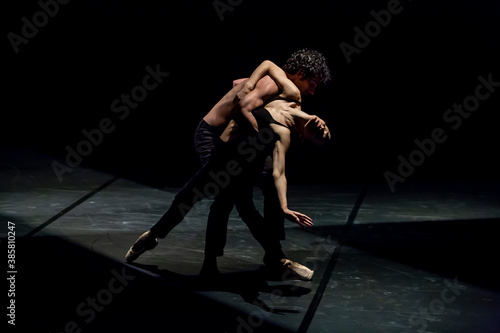 Male and femal dancer performing contemporary ballet on black stage photo