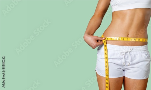 Slim young woman measuring her thin waist with a tape measure
