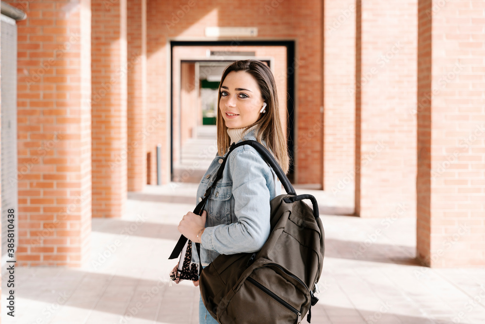 Smiling university student with bag and book standing in campus Smiling university student with bag and book standing in campus