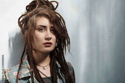 Young Rastafarian woman standing against gray wall photo