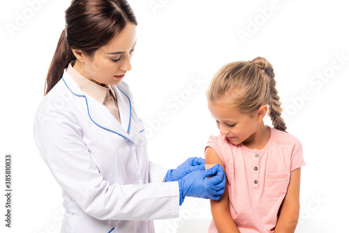 Doctor in latex gloves applying patch on hand of girl isolated on white