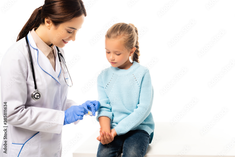 Smiling pediatrician holding patch near hand of kid isolated on white Smiling pediatrician holding patch near hand of kid isolated on white