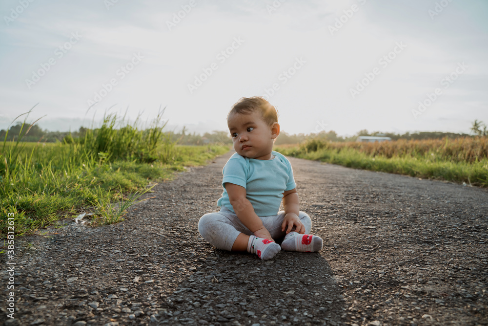 portrait of adorable asian baby sitting alone on empty road portrait of adorable asian baby sitting alone on empty road