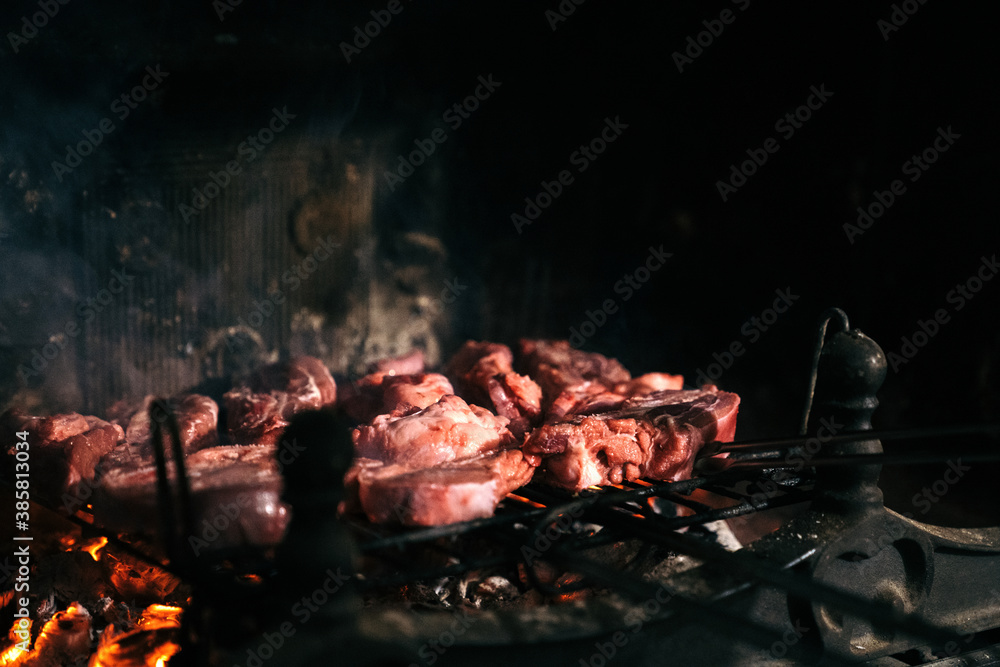 Grilled meat in the fireplace of his home. Raw beef on a barbecue grill with the coals underneath.