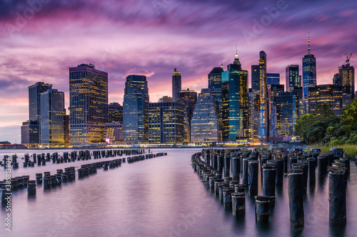 Scenic view of mooring posts in East River with Lower Manhattan in background during sunset