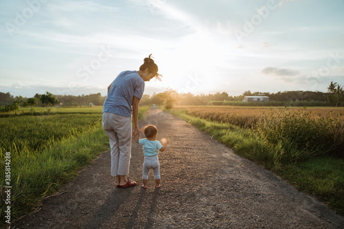 Принти на полотні mother help her baby to walk her first step on country road