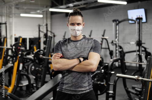 Pandemic gym - man working out with protective face mask during coronavirus outbreak