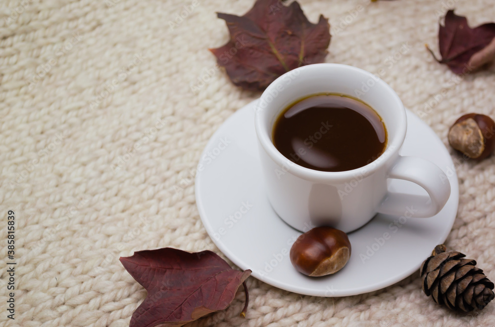 Autumn, a Cup of espresso coffee with leaves on a woolen knitted sweater. The concept of the season.