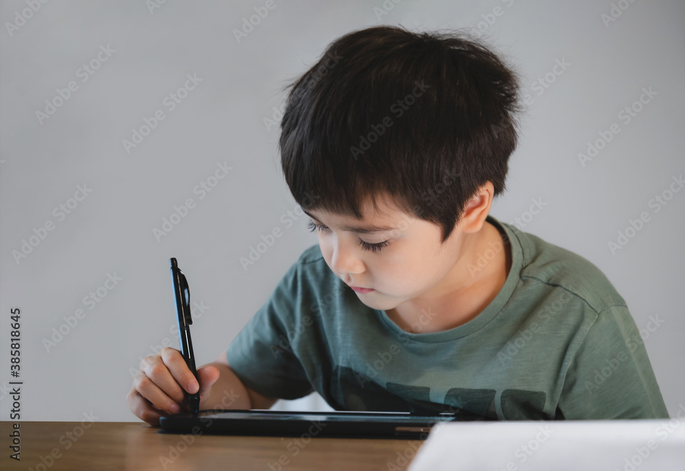 Kid self isolation using tablet for his homework,Child boy using digital tablet searching information on internet during covid 19 lock down,Home schooling,Social Distance,E-learning online education Kid self isolation using tablet for his homework,Child boy using digital tablet searching information on internet during covid 19 lock down,Home schooling,Social Distance,E-learning online education