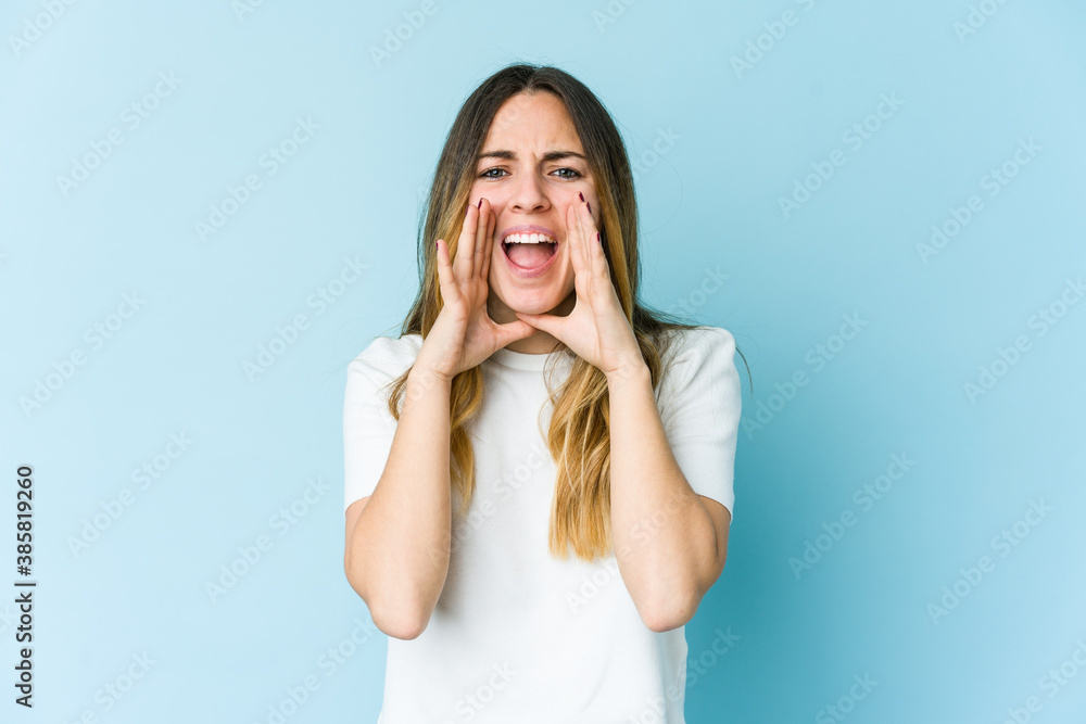Young caucasian woman isolated on blue background shouting excited to front. Young caucasian woman isolated on blue background shouting excited to front.