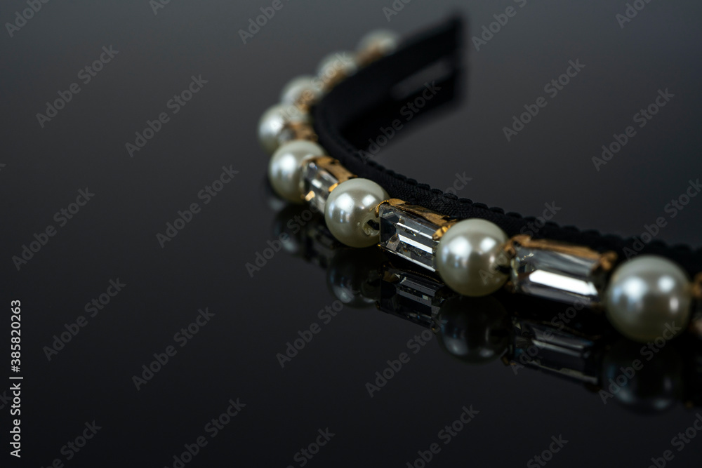 Accessory for head on black background. Pearls and white crystals in a golden holder Accessory for head on black background. Pearls and white crystals in a golden holder