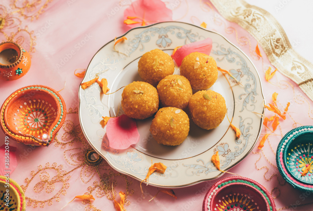 Bundi Laddu served in a plate along with traditional Indian Diyas. An Indian festive food and background. Bundi Laddu served in a plate along with traditional Indian Diyas. An Indian festive food and background.