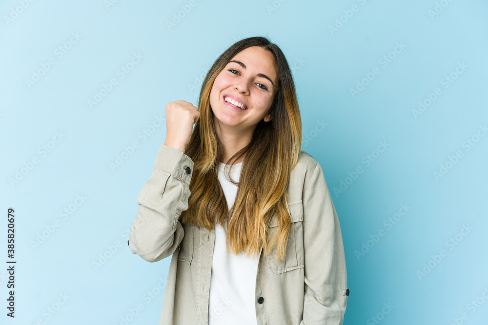 Young caucasian woman isolated on blue background celebrating a victory, passion and enthusiasm, happy expression.