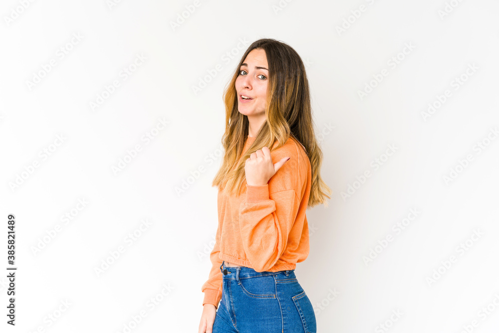 Fototapeta premium Young caucasian woman isolated on white background points with thumb finger away, laughing and carefree.