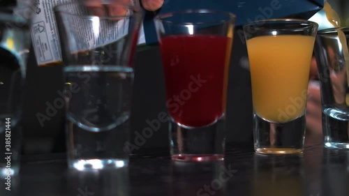 bartender pours colorful drinks into small glasses close-up