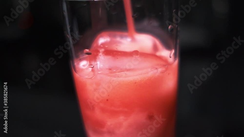 a pink drink is poured into a glass with ice close-up slow motion