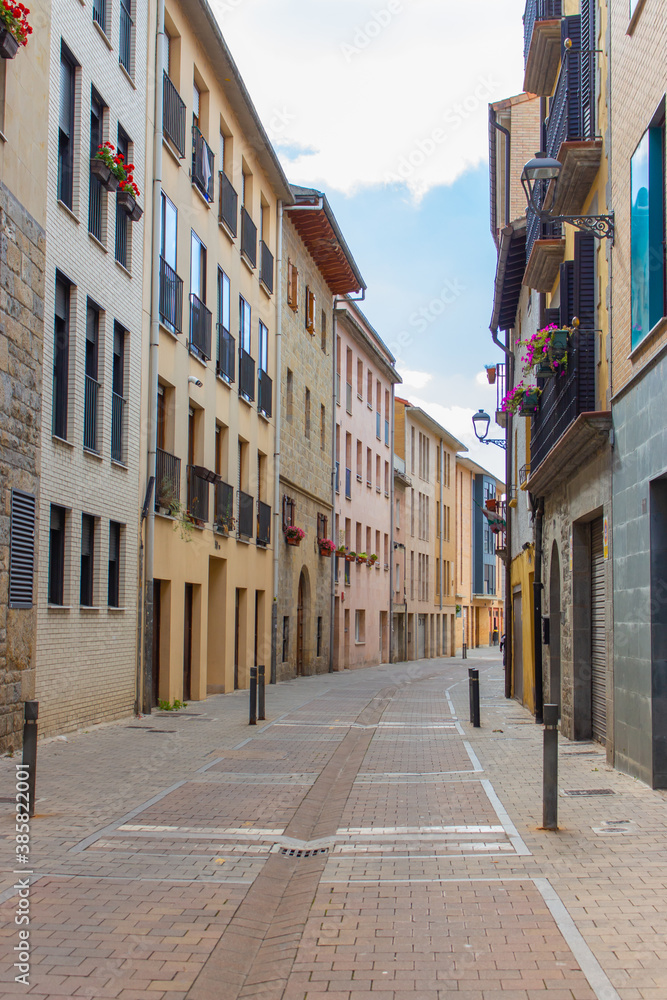 Empty narrow street in old town, Spain. Traditional facade of buildings in small town in Europe. House exterior with flowers and street lamps. Travel in Europe. Town without people. Empty city street.